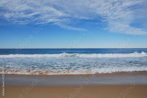 Scenery at the beach shows clean sand and deep blue sea