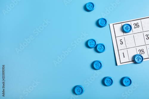 Bingo balls and cards on blue background with copy space.