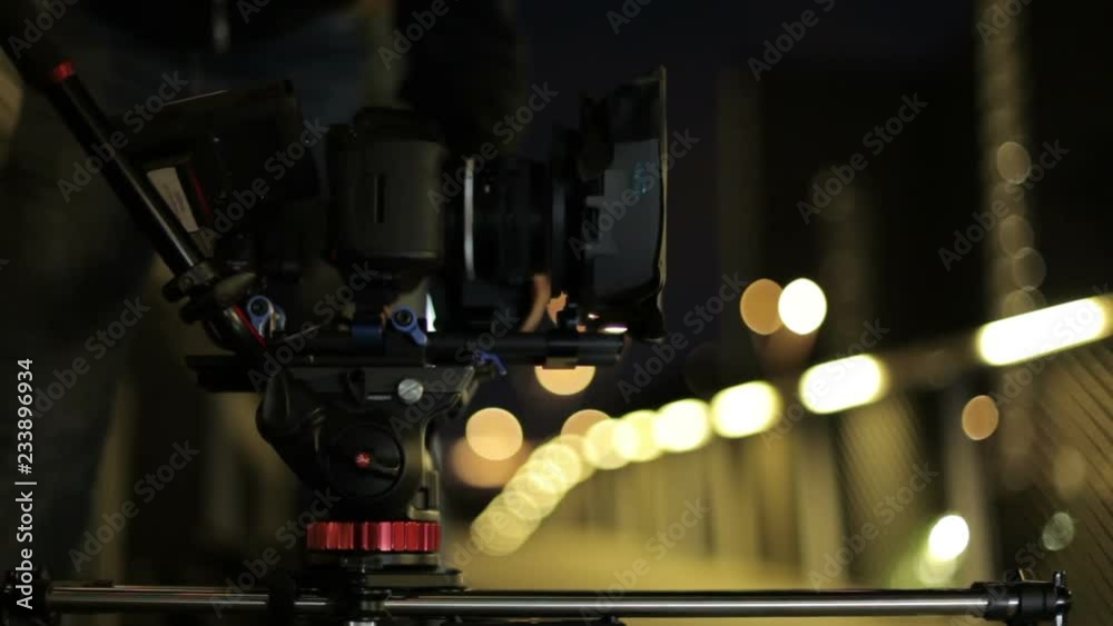 video dslr camera advancing on slider with lights and a fence in background. behind the scenes video production 