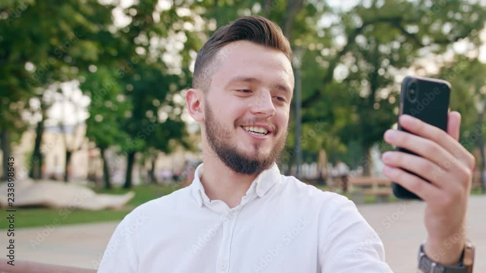 An attractive young man using a phone in town for a voicecall. Close-up shot. Soft focus An attractive young man using a phone in town for a voicecall. Close-up shot. Soft focus