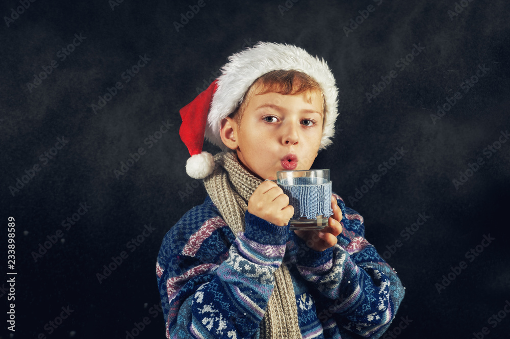 portrait of a boy in winter, a child in a Santa hat and a warm sweater . Merry Christmas