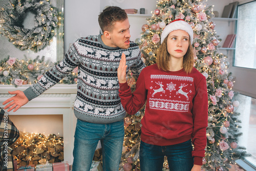 Picture of angry man stand besides woman and screams at her. She holds palm close to him. Woman is upset. She cries a bit.