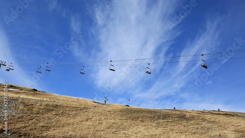Footage of a ski lift in a mountainous area without snow in the winter.