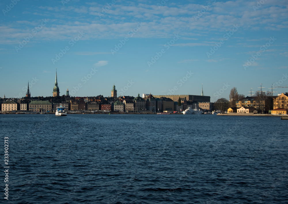 Water view over Stockholm an winter day, snowy, sun and clear sky over boats and landmark