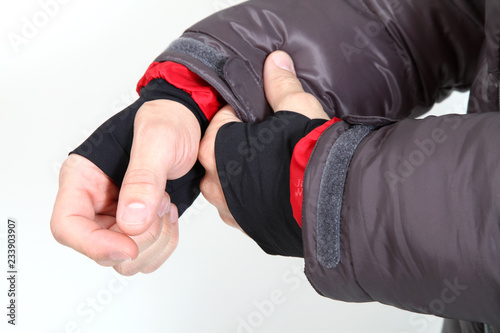 hands fixing sleeves of a grey winter jacket in front of a white background