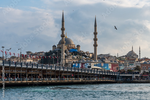 New Mosque in Istanbul with flying birds and crowd of people at the Galata bridge in the foreground