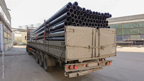 Old truck loaded with black plastic pipes. Back view.