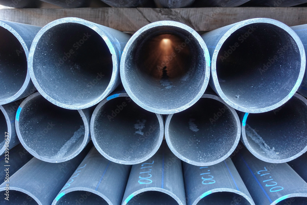 Stacks of black plastic pipes. Round ends close up.
