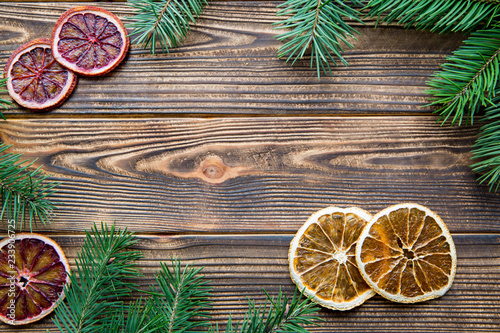 Dried orange slices and fir tree branches frame. Brown wooden table background. Free space for Christmas greeting. 