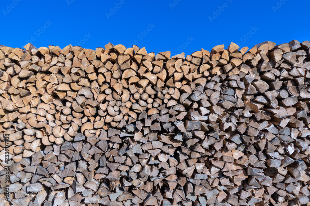 Großer Holzstoß mit vielen kleinen Scheiten vor blauem Himmel
