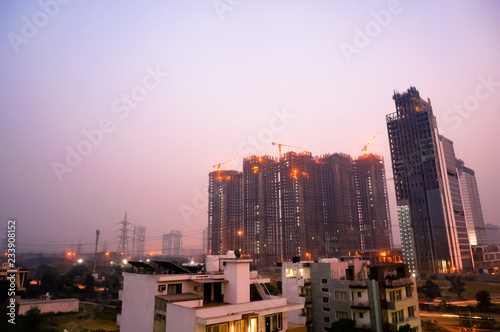 Under construction skyscraper shot at dusk in gurgaon, noida, lucknow, jaipur, mumbai, gurugram NCR. These housing and office buildings for real estate are being developed to house the ever increasing