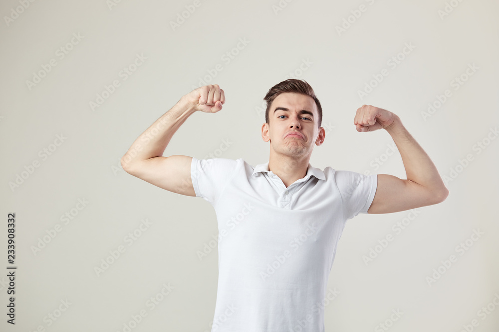 Guy dressed in a white t-shirt and jeans is full of strength and energy on a white background in the studio Guy dressed in a white t-shirt and jeans is full of strength and energy on a white background in the studio