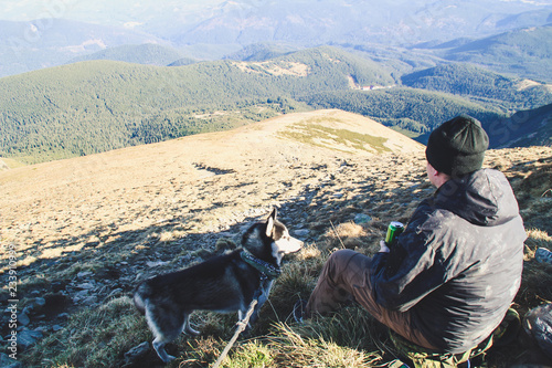 The boy travels with husky. Ukrainian Carpathian Mountains. Top of the mountain.  Black and white dog. Hiking with dog. © Yaroslav