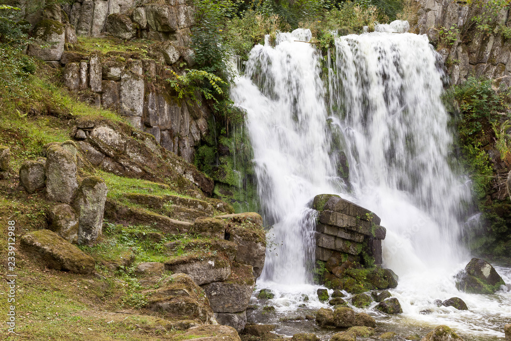 Obraz premium Beautiful waterfall with stone formation and plants on a mountain in the rainforest.