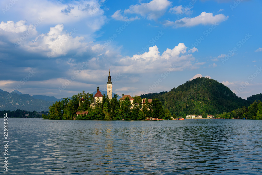 Iconic landscape view of beautiful St. Marys Church of Assumption on small island,lake Bled in Slovenia .Bled Castle on background. Summer scene travel Slovenia concept. Tourist popular attraction