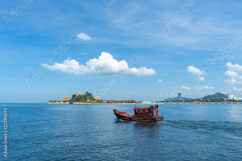 The view of the small island in the distance with the sea and the clear sky with fog with red fishing boat sailing in the ocean. photo