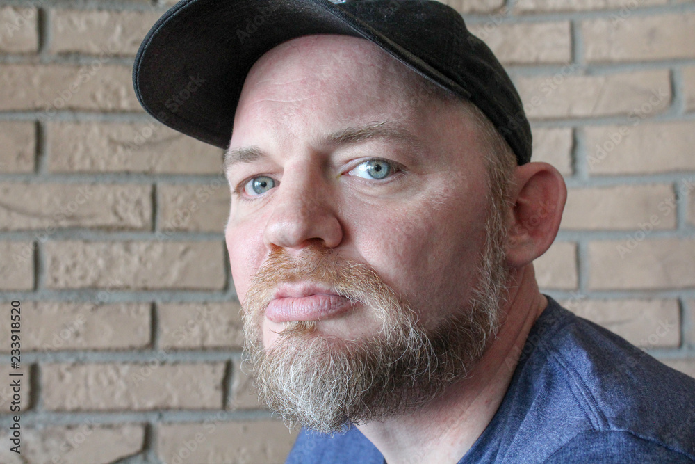 Portrait of man with blue eyes. Intense look, isolated with a brick wall background Portrait of man with blue eyes. Intense look, isolated with a brick wall background