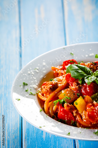 Pasta with meat, tomato sauce and vegetables on wooden table