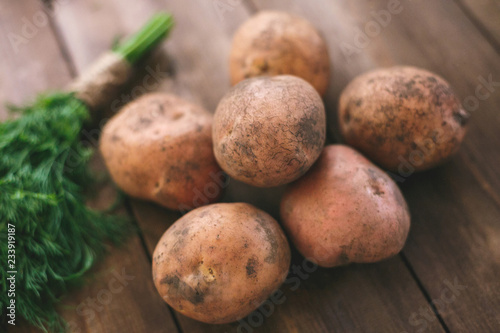 Potatoes and dill lies on a modern table made of natural wood