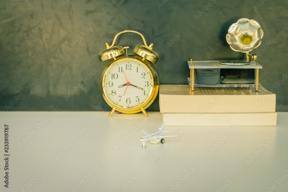 alarm clock old gold and book, gramophone, plastic plane jet toy passenger. over white on black background. with copy space add text. color vintage style tone alarm clock old gold and book, gramophone, plastic plane jet toy passenger. over white on black background. with copy space add text. color vintage style tone