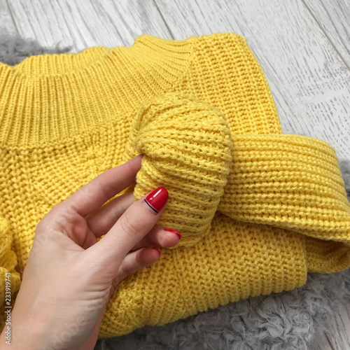 Folded bright yellow sweater on a wooden background