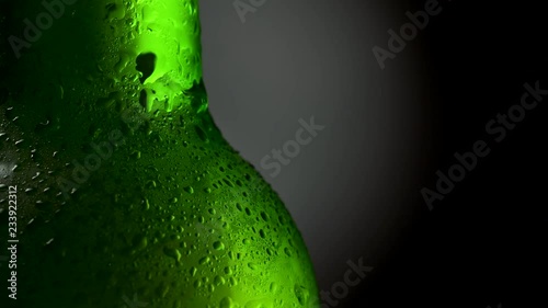 Close up shot of cold beer green bottle with water drops. Rotation 360, black background. UHD, 4K