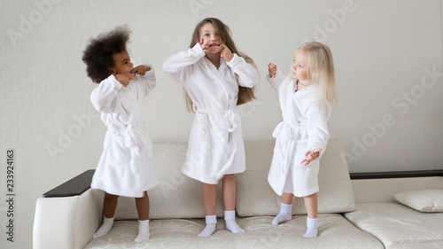 Girls indulge stick out tongue. Little girls in white coats playing make funny faces grimaces facial expressions.