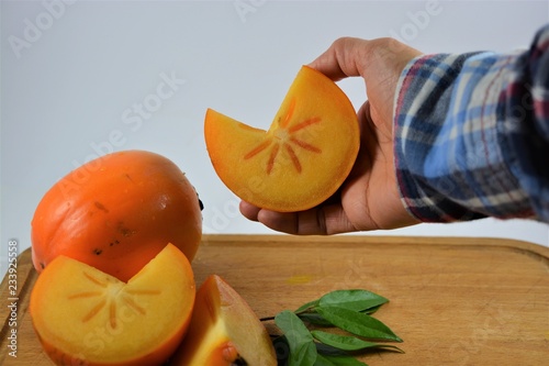 A cut persimmon fruit being held
