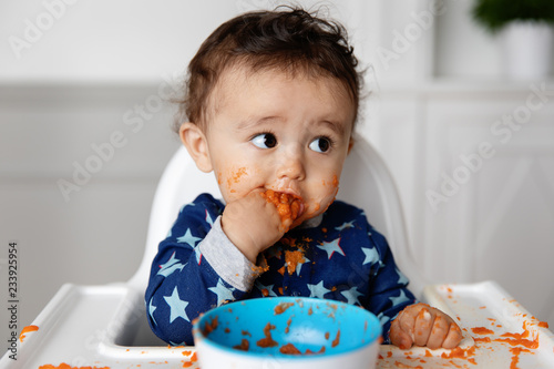Baby eating carrot puree with his hands photo