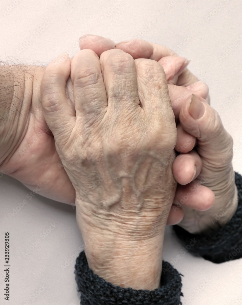 Fototapeta premium Hands of old woman. With a hand of a man (son, grandson, doctor, helper) 