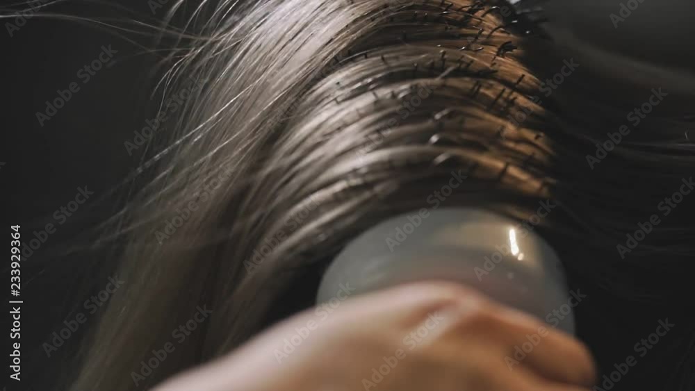 Close-up shot of woman having her hair drying and brushing in hair salon in slow motion.