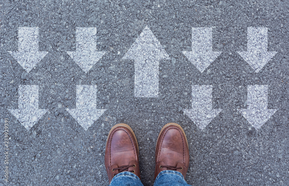 Top view of man wearing shoes choosing a way marked with arrows. Chooses the right path concept.