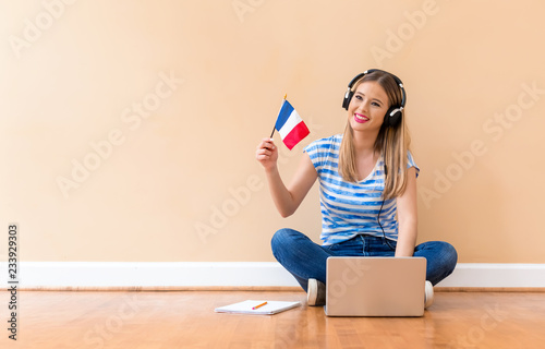 Young woman with French flag using a laptop computer against a big interior wall photo