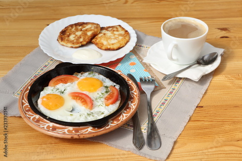 Fried eggs with tomatoes and coffee with cheesecakes 