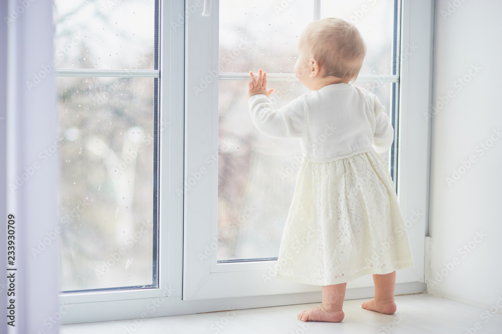 blonde curly toddler Baby girl looking through a window. blonde curly toddler Baby girl looking through a window.