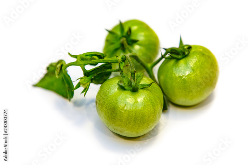 Natural organic tomatoes, green and orange on white background with shadow.