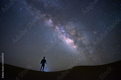 Milky way galaxy with a man standing and watching at Tar desert, Jaisalmer, India. Astro photography. © tanarch