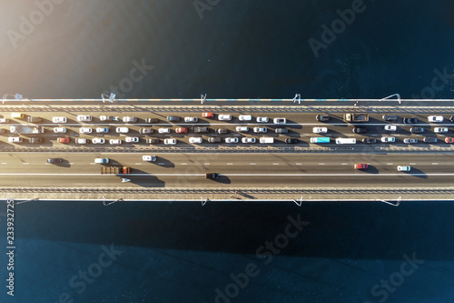 Aerial view of road bridge across river with heavy traffic jam in one direction. Rush hour with mash and overloading of road infrastructure. Resolving of car traffic jam