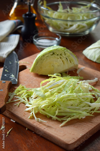 Cooking sauerkraut or salad on wooden background. Step 1 - Chop Cabbage. Fermented preserved vegetables food concept.
