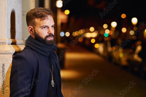 Hombre joven con barba y elegante en la calle, en una noche de invierno