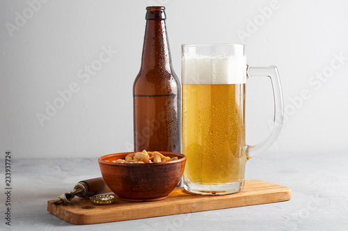 Obraz na płótnie Lager beer pouring in glass and bottle with salted peanuts on gray concrete background w salonie