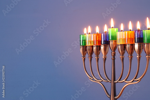 image of jewish holiday Hanukkah background with menorah (traditional candelabra) and colorful oil candles.