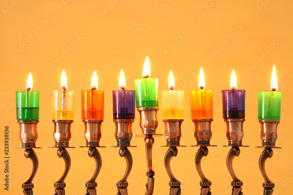 Fototapeta premium image of jewish holiday Hanukkah background with menorah (traditional candelabra) and colorful oil candles.