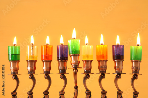image of jewish holiday Hanukkah background with menorah (traditional candelabra) and colorful oil candles.