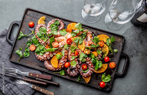 Whole octopus salad with orange, tomatoes and cress salad served on board with wine