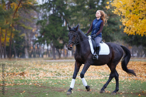 Young rider girl galloping on bay stallion in park © skumer