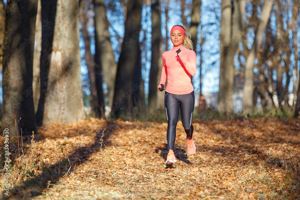 Young woman jogging on trail in autumn park