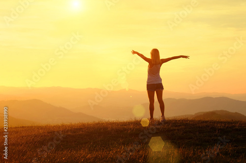 Happy woman with open arms stay on the peak of the mountain 