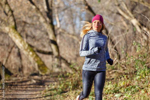 Young woman jogging on trail in autumn park