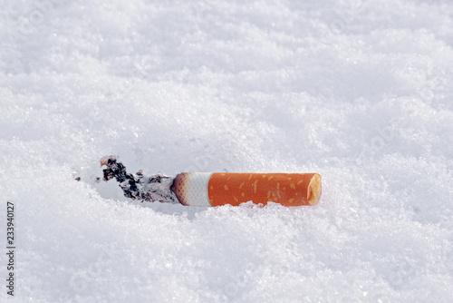 closeup of smoking cigarette butt on a snow with copy space